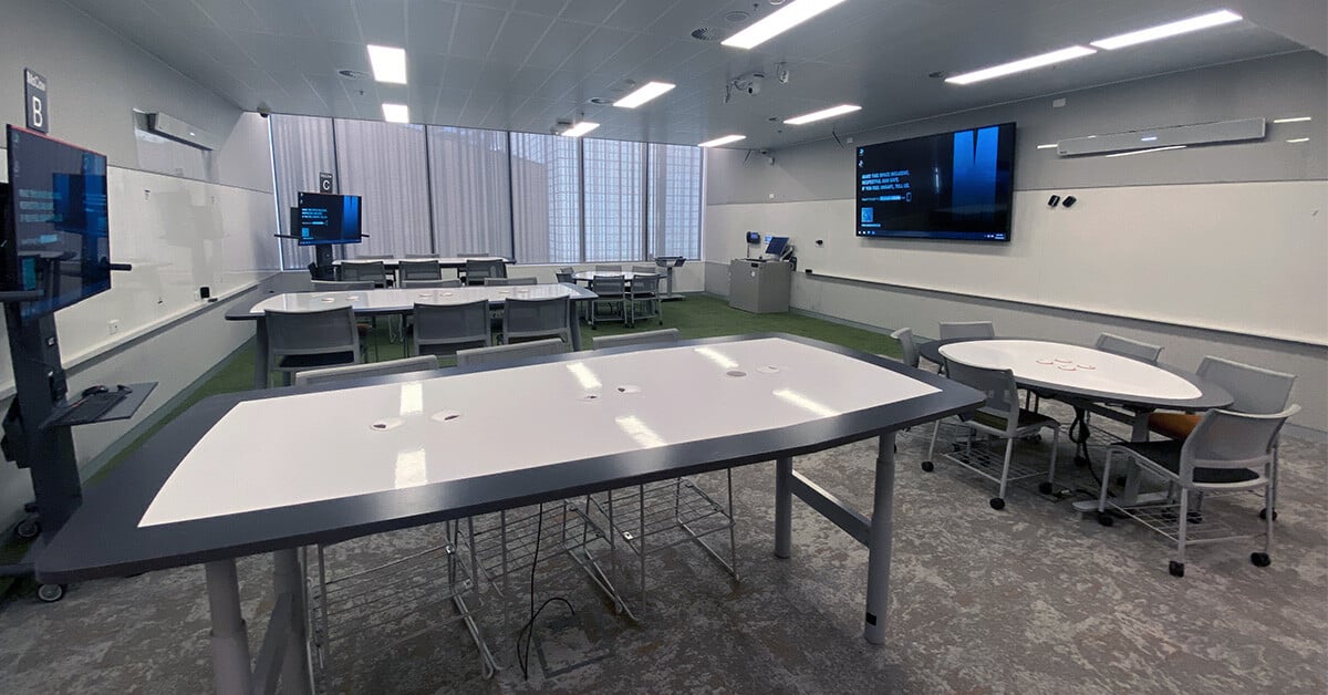 A collaborative higher ed classroom at Monash University with several tables, displays and a Nureva audio system.
